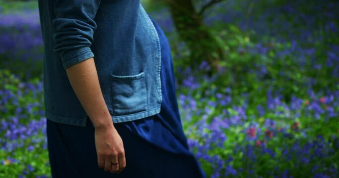 Pregnant woman walking in a meadow of bluebells