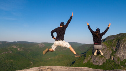 Young couple jumping at the summit of "La Chouenne" mountain in Charlevoix, Quebec