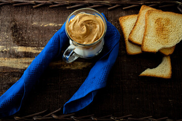 
Dalgona coffee in glass cup with blue napkin and toast