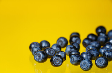 Blueberries are highlighted on a yellow background. Blueberry border design. Ripe and juicy fresh picked blueberries close. Copy space. Top view or flat lay