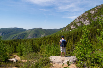 Naklejka na ściany i meble Les Grands-Jardins national park, Canada - june 2020 : back view of a hiker admiring the landscape