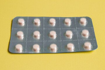 Expired blister pack of pills on yellow background.
Unused, unwanted, or expired medicines on a table.