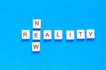 NEW REALITY. the words new reality are written in wooden letters on a blue background. flat layout. top view