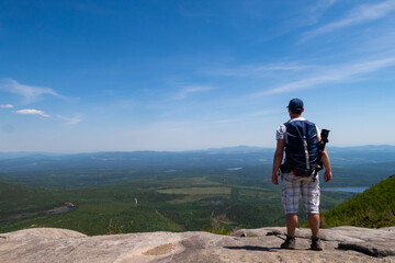 Grands-Jardins national park, Canada - june 2020: Young man with a backpack admiring the view