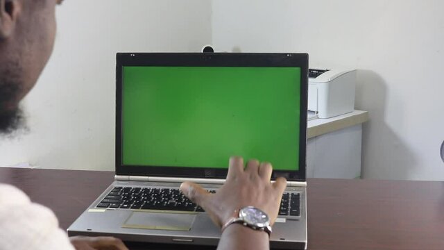 Office, Enter and Next: A man showing the steps to a business process in front of a green screen laptop computer in his well lit small office.