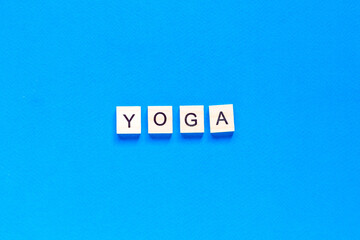 The word YOGA written in wooden letterpress type on a blue background. flat layout. top view.