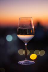 A glass of champagne on the blurred natural background of the sunset. A glass of white sparkling wine close-up. Festive evening. Soft focus, beautiful bokeh.