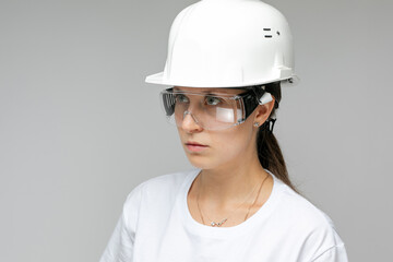 Smiling confident woman architect in a construction helmet on a light background