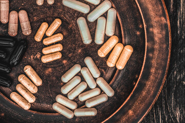 Multivitamin pills on a clay plate, on a vintage wooden table