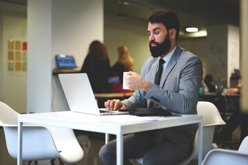 Young handsome executive manager of marketing company chatting in social networks enjoying coffee...