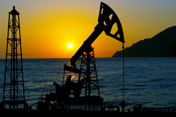 Silhouette of oil derricks on a sunset background. Oil and gas production concept. With place for...