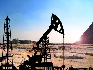 Silhouette of oil derricks on the background of the pyramids. Oil and gas production concept. With...