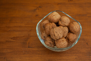 Glass jar full of walnuts with wooden background. Top view. Space for text