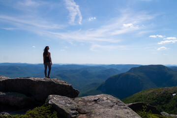 Naklejka na ściany i meble Back view of a young woman standing at the summit of the 