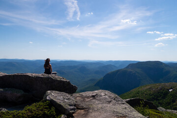 Young woman sitting at the summit of the "Mont-du-lac-des-cygnes" in Charlevoix, Quebec