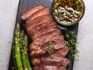 juicy, grilled, sliced beef steak, with roasted asparagus, close up, sauce olive oil herbs and spices
