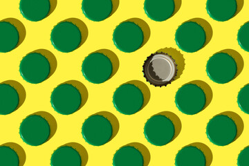 Colorful pattern: green metal bottle caps on yellow background, one caps is inverted, flat lay