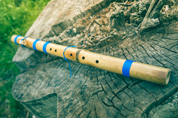 North American traditional flute Pimak. Traditional love flute Pimak of Indigenous peoples of the North Americas. Flute lies on a stump. Made from bamboo. © decorator