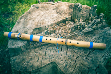 North American traditional flute Pimak. Traditional love flute Pimak of Indigenous peoples of the North Americas. Flute lies on a stump. Made from bamboo. © decorator