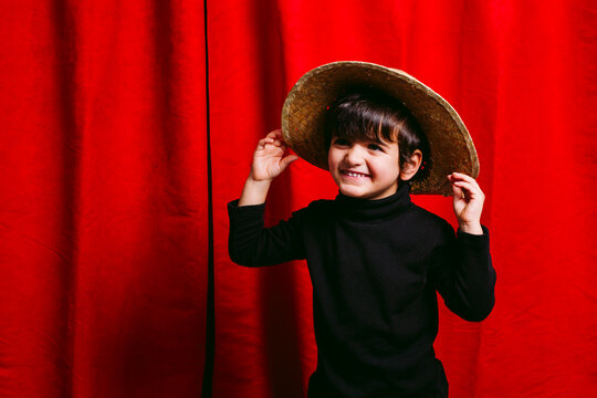 Three year old boy, wearing black clothes, happy with his straw hut