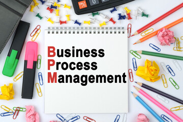 On the table is a calculator, diary, markers, pencils and a notebook with the inscription - Business Process Management