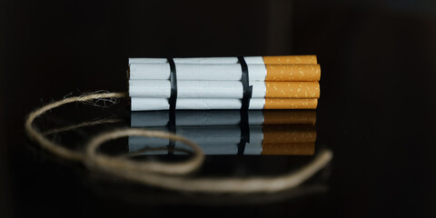Cigarettes are twisted into a dynamite checker with a filament on a black reflective surface.