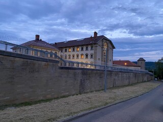 Gefängnisgebäude hinter dicken Mauer mit Stacheldraht zur blauen Stunde
