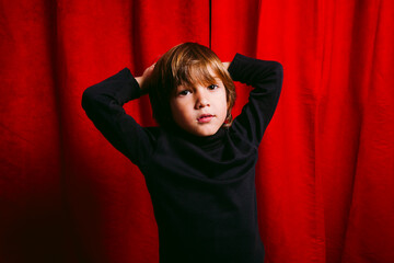 Five years old boy, against a red curtain