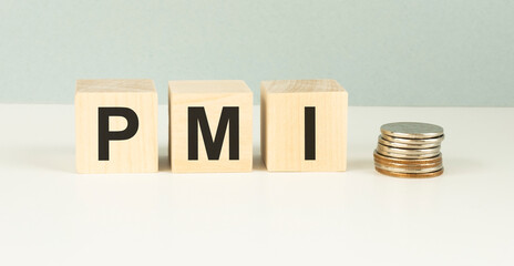 Text PMI on wood cube with gold coins on the table, economic data concept.