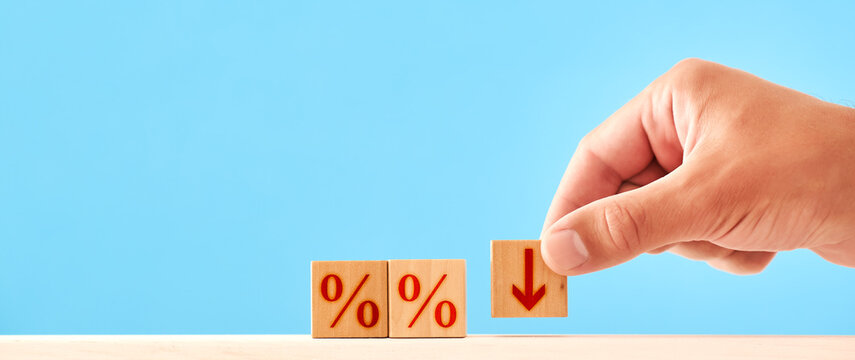 Percentage Down concept. man puts a wooden block with a down arrow next to blocks with percent symbols