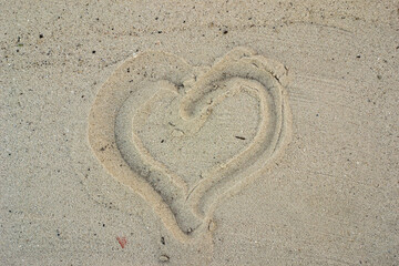 Fototapeta na wymiar a heart is drawn in the sand. Beach background. Top view