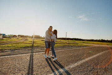 Obraz premium Portrait of a couple in love walking along the road. A man and a woman enjoy a vacation in the countryside. Young people walk in nature.