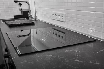 modern white kitchen with black countertop and induction hob