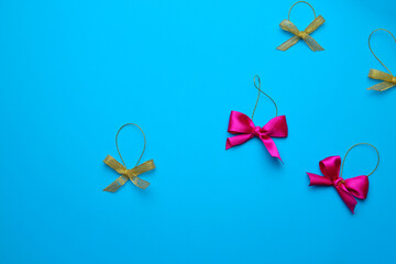 Purple and gold Christmas bows lie in chaotic order on a blue background. Copy space