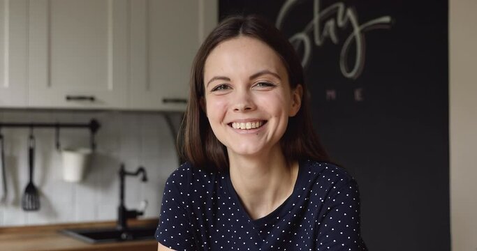 Headshot portrait attractive young woman standing posing at home kitchen smiling looking at camera, laughing feels carefree and happy. Concept of video event conference user, enjoy distant interaction