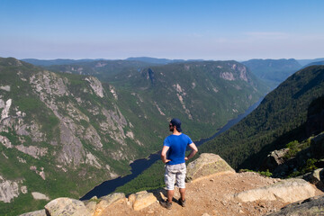 Obraz premium Hautes-gorges-de-la-rivière-Malbaie national park, Canada - june 2020 : young man standing at the top of the 
