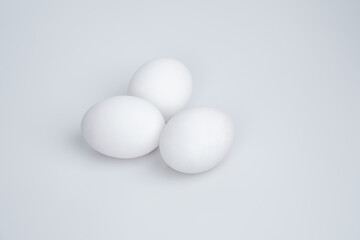Three white eggs on a white background
