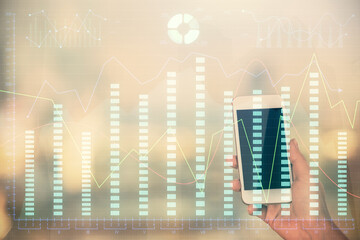 Double exposure of forex chart sketch hologram and woman holding and using a mobile device. Stock market concept.