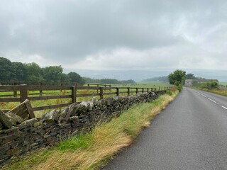 A country road, with dry stone walls, fields, and heavy rain clouds near, Slaithwaite, Huddersfield, UK