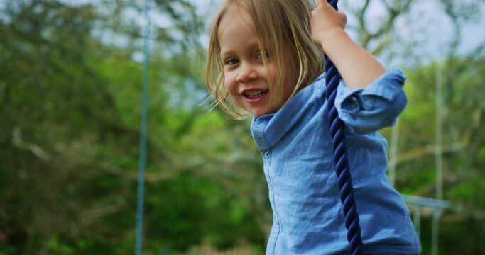 Preschooler boy playing on rope swing in nature