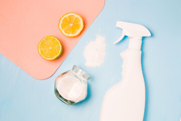 a white bottle of spray without a label, half lemon and lime, sprinkled soda and a glass jar of...