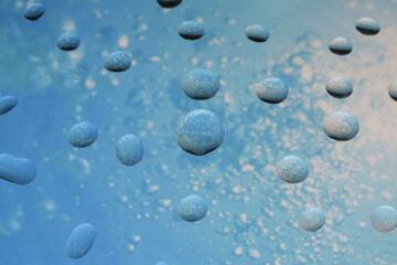A lot of water drops lie on the surface of the bent glass and reflect the picture below them