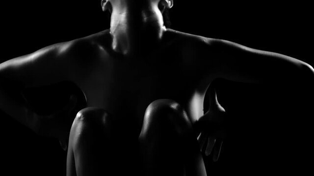 Silhouette of a naked woman against black background. 