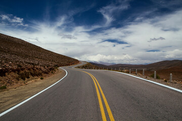 Getaway. Artistic view of the asphalt road across the desert and hills under a dramatic sky.  