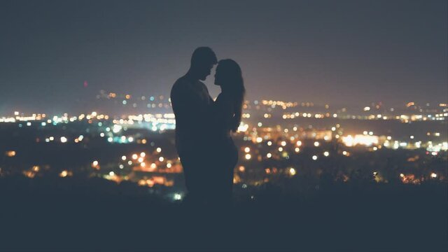 The young couple kisses on the night city background