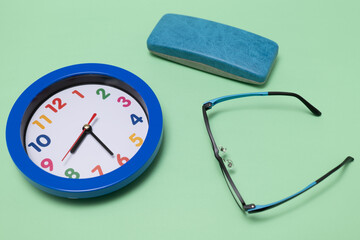 緑の背景の掛け時計、メガネとメガネケース