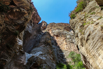 Inside of a natural canyon, huge cliff, sediment layers are visible