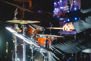 View of drum set kit on a stage during jazz rock show performance, with band performing in the...