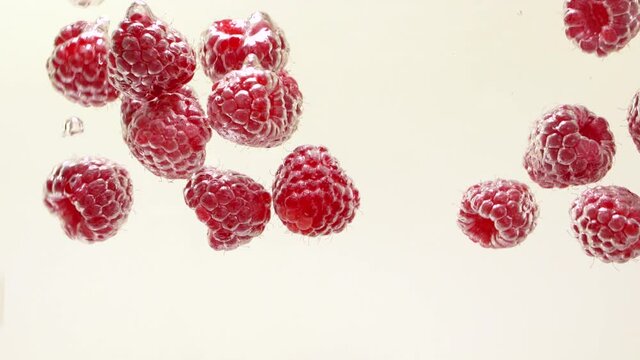 Raspberries falls into the water. Ripe raspberry splash in the water, closeup.