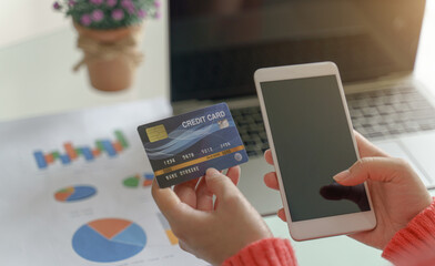 Woman holding mock up credit card  while using smartphone and laptop for shopping online by credit card.Shopping and payment online.